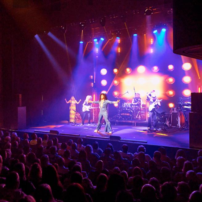 Performers on stage to a full crowd.