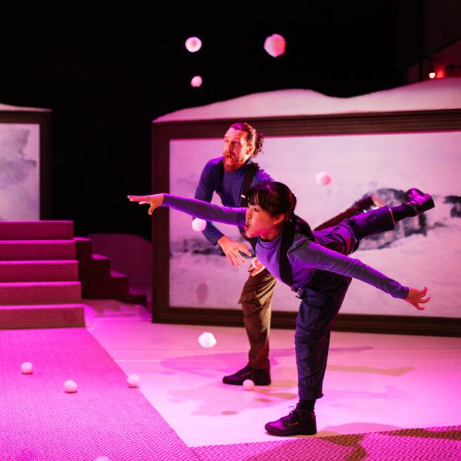 Two dancers wearing ski suits throwing snowballs on stage 