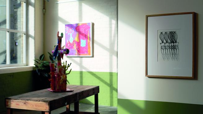image of sun shining through gallery windows highlighting art work on the walls and table