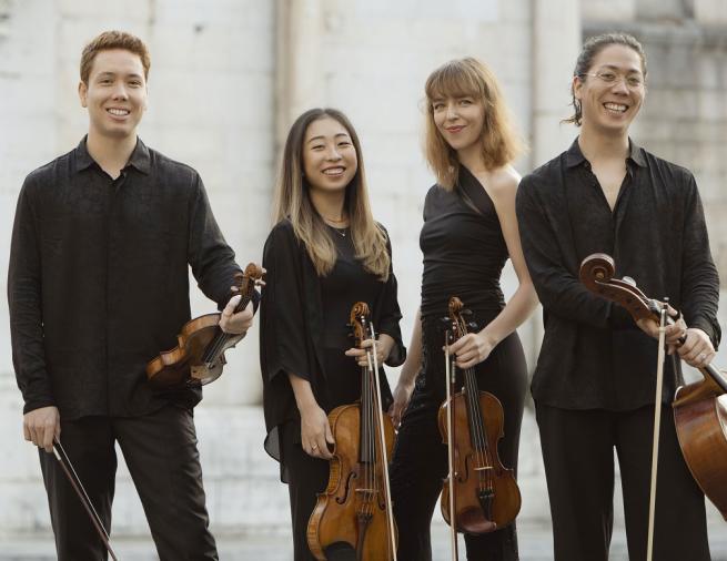  Four classical musicians stood holding their instruments. 