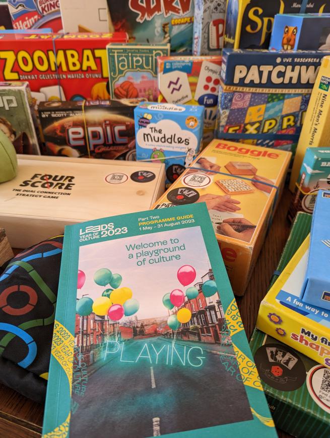 Leeds 2023 'Playing' programme surrounded by board games. 