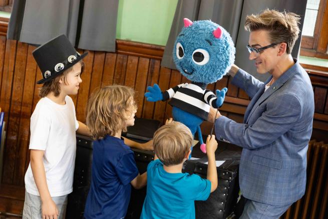 A person showing a puppet to some children.