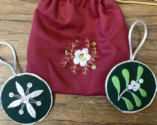 A red embroidered bag and two small embroidered hoops.