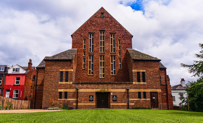 Tall red-brick building with think, rectangular windows and dark-wood double doors. On either side of the doors sits the LEFT BANK logo, white text against a black background.