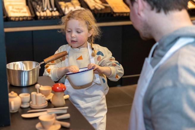 photograph of a young girl playing with toy pots and pans in an exhibition