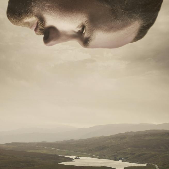 A man looking down on a landscape below him. 
