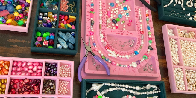 Beads and pearls for a jewellery and drinks workshop: a table displaying a variety of exquisite colorful assortment of materials for creating stunning accessories.