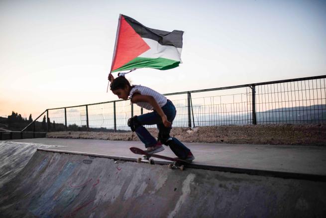 A skateboarder with a Palestinian flag