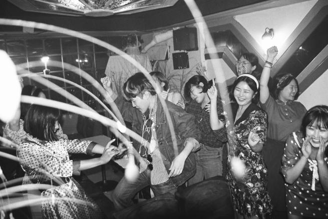 Black and white photo of women dancing and smiling in a bar.