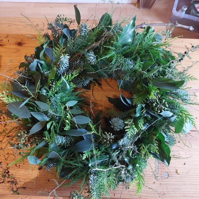 A photograph of a natural wreath made using green foliage