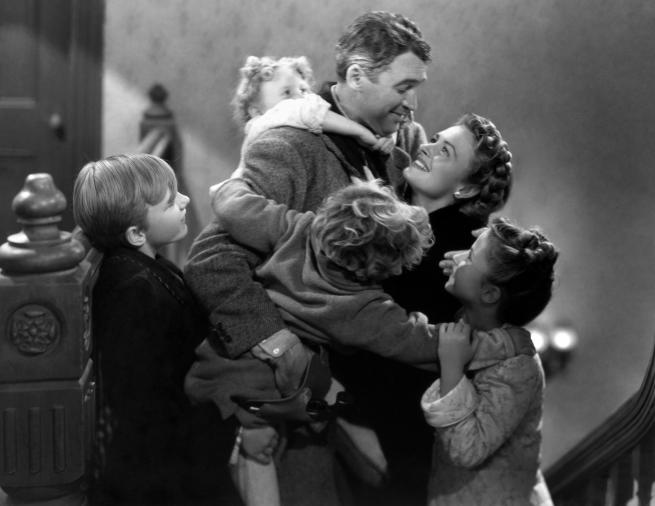 Black and white image of a man hugging his wife and four children.