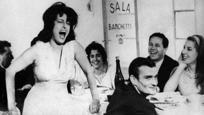 Black and white photo of a woman screaming in a restaurant while men and women at a table watch.