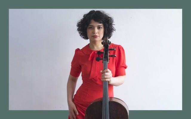 A woman in a red dress holding a cello.