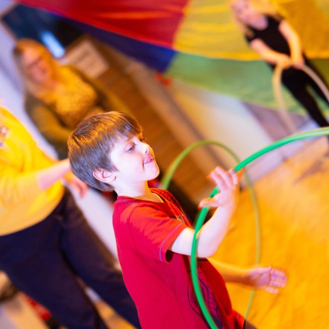 A boy enjoying learning hoop skills in a Circus Family class