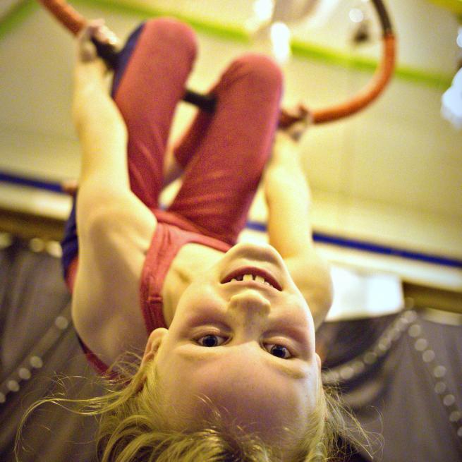 A girl enjoying an aerial class on a hoop suspended from the ceiling