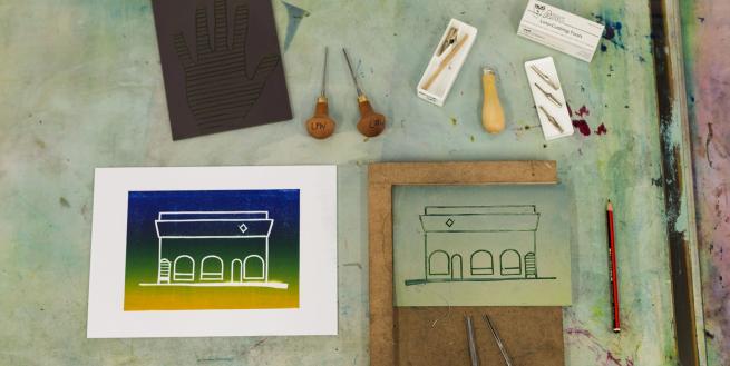 An image showing a lino block and a multi-colour print along with the tools for carving into the lino.