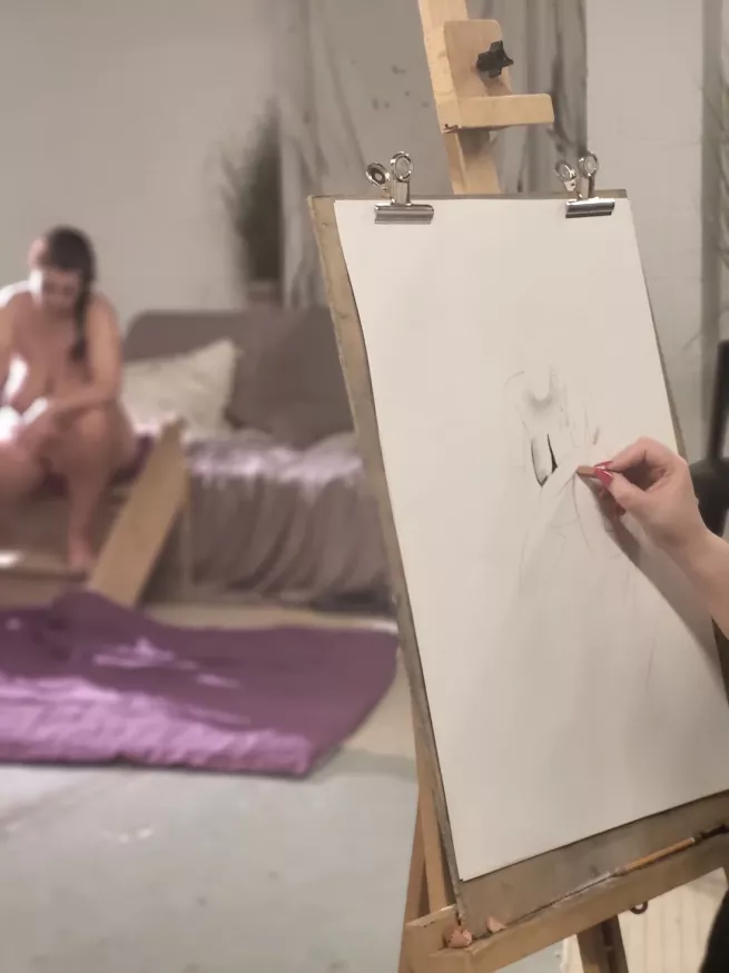 A point of view of an artist at an easel, with the life model in background