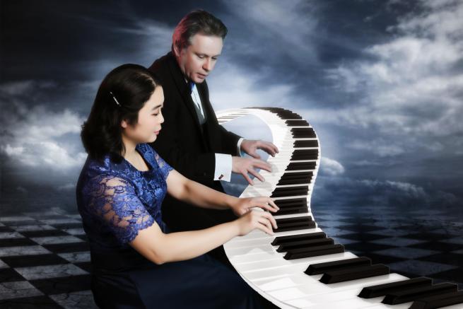 A male and female musician both playing the piano. 