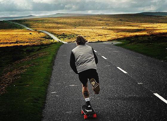 Skateboarder riding the open road in the Scottish Highlands