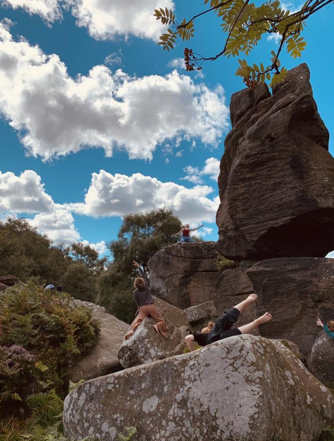 Large rocks and blue skies scattered with people dancing among them