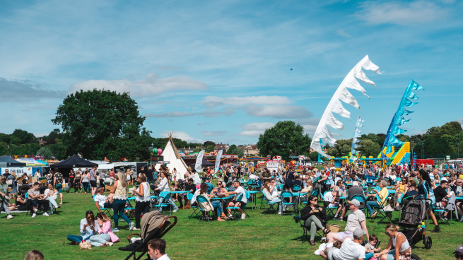 We're focused on a snapshot of last years busy 'Riverside Food Festival' whereby festival goers are lounged on deckchairs enjoying the live entertainment!