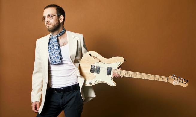 Male wearing glasses holding guitar