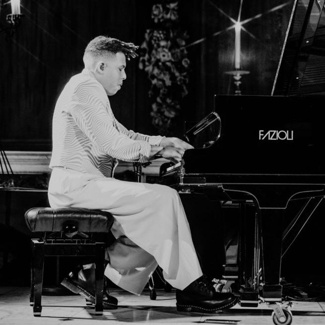 Black and white image of Tokio playing piano on stage.