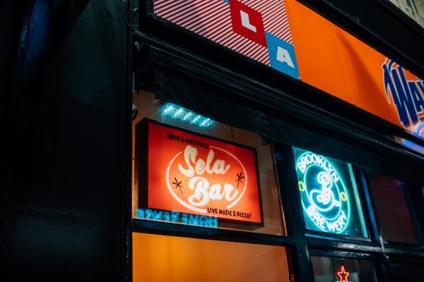 Sela Bar front door entrance with red light box & logo.