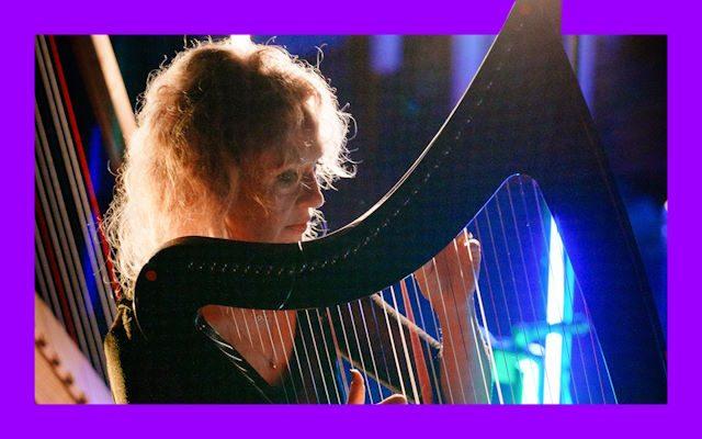 A woman with curly hair playing the harp.