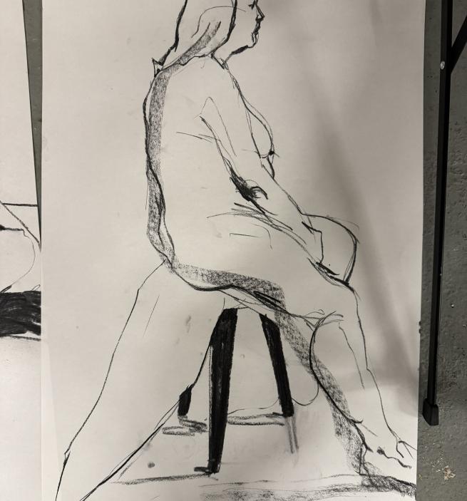 A side profile of a female life model sat on a stool 