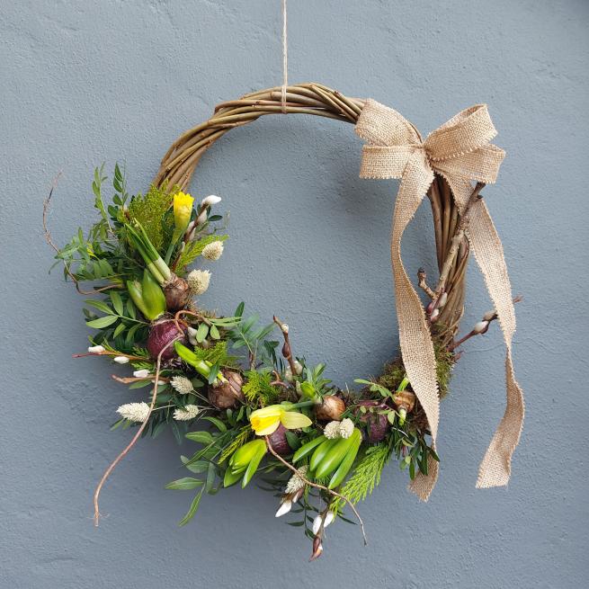 A living spring wreath on a willow frame with spring seasonal foliage