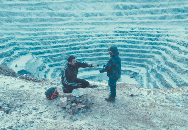 A mjan and his son knelt down in front of a disused quarry