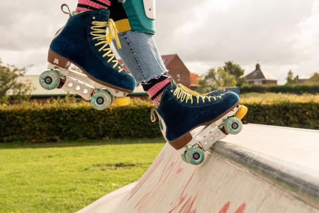 A close up of  pair of skates performing a plate stall in an outdoor skate park 