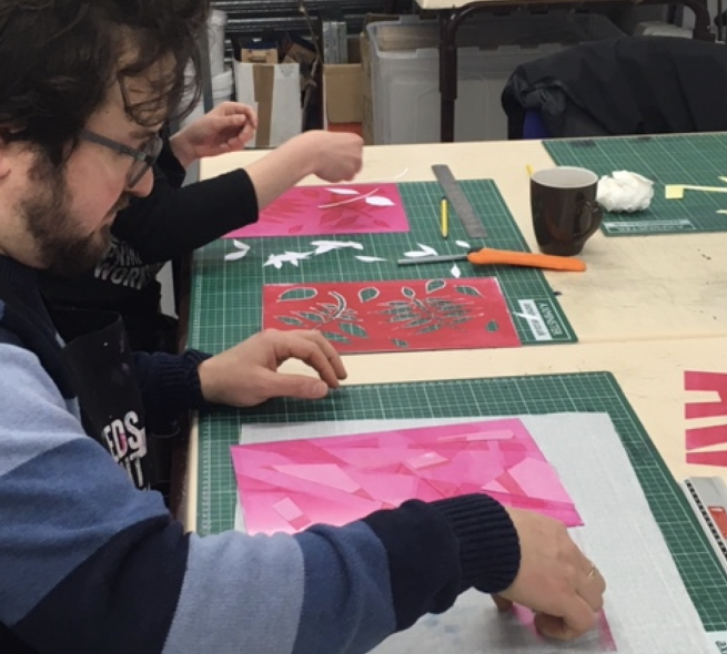 A group of people creating monoprints by cutting shapes from paper
