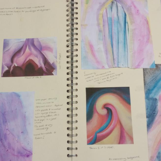 A close up of a sketchbook with swirly designs in pinks and purples