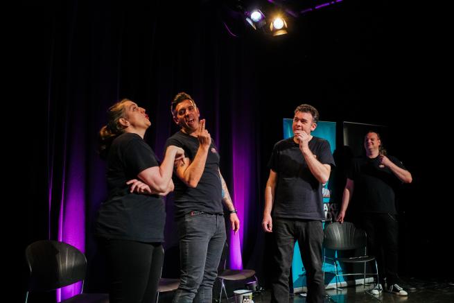 An image of the four improv performers acting out a scene