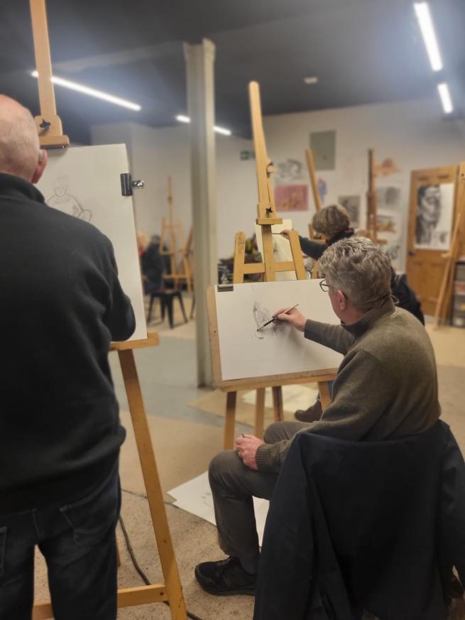 Artists sat at easels drawing a life model
