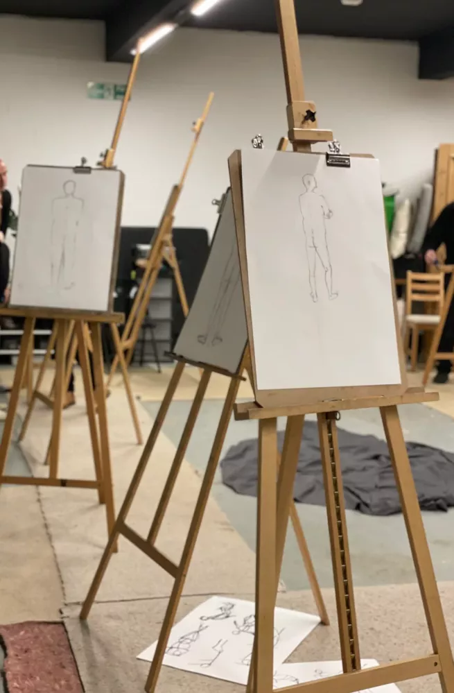 An art studio with easels showing drawings of a life model