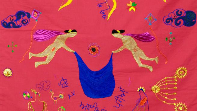 A section of Indian inspired folk embroidery - a dark red cloth with two winged figures holding a blue cloth