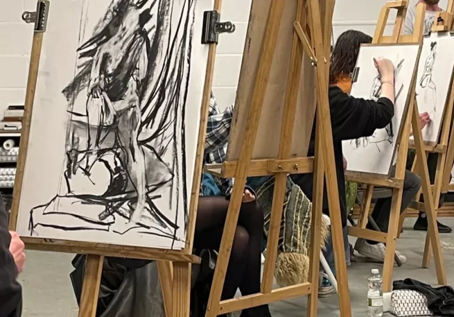 easels in an art studio with charcoal drawings of life models on them
