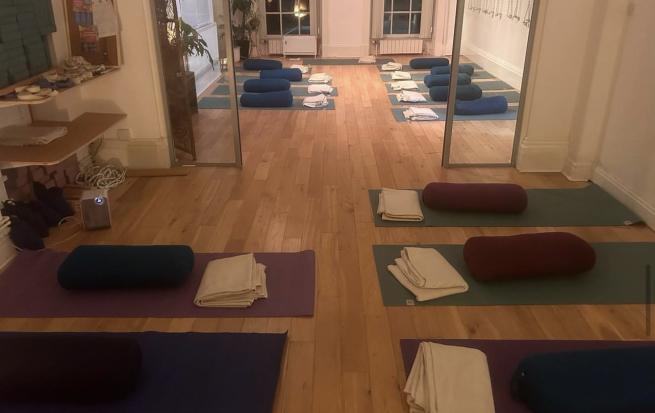 spacious room with mats laid out with yoga equipment on.