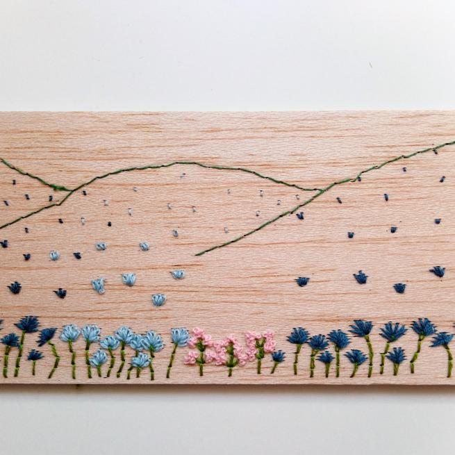 A landscape stitched onto wood