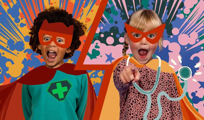 Two children dressed as superheroes in front of a multicoloured background.