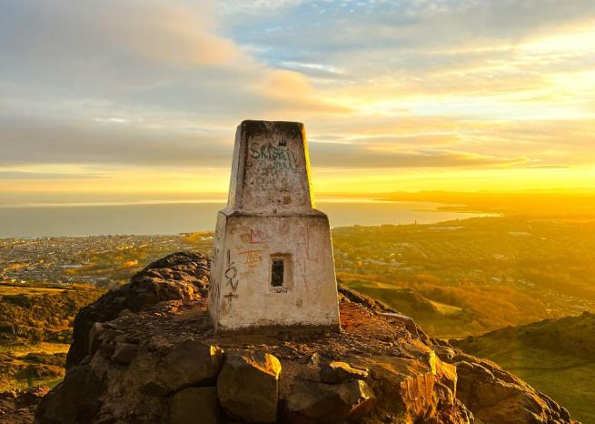 Trig point and view from Arthur's Seat with golden sunlight