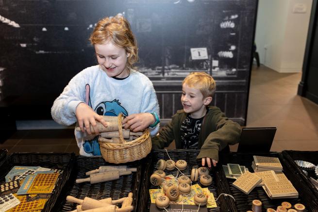 A colour image of two children playing in a replica shop.
