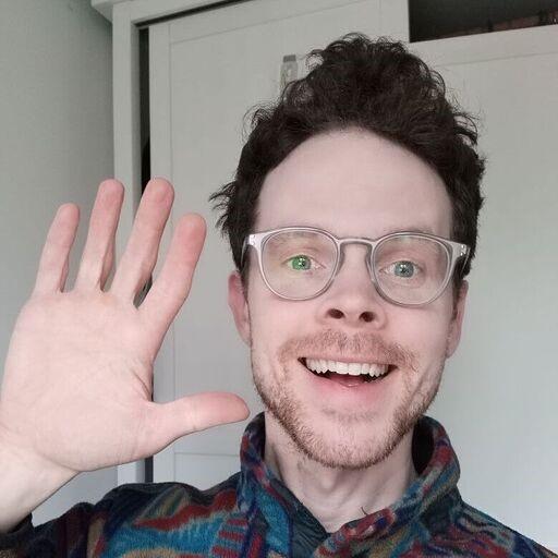 A photo of Dr Dan Lever, holding his hand up