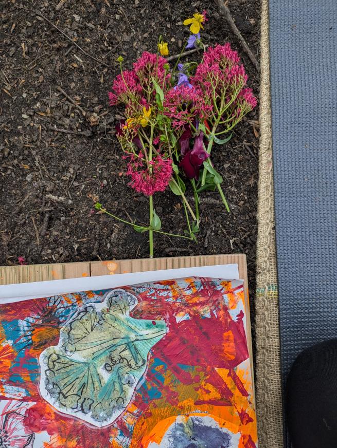 Bright summer flowers, creative colourful art and a yoga mat laying on soil