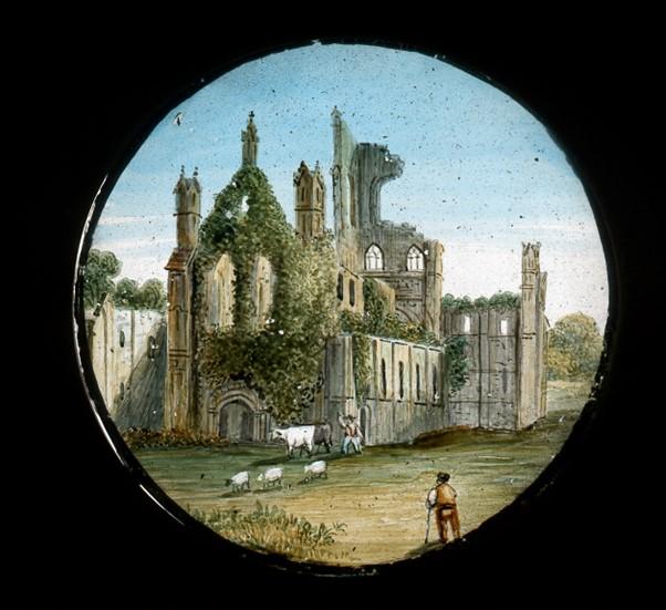 A glass lantern slide of Kirkstall Abbey nave. Ivy grows on the entrance. Sheep and a farmer are in the foreground