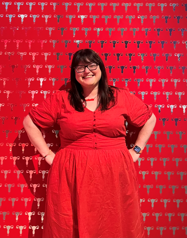 Chella Quint in a red dress in front of a red and silver background