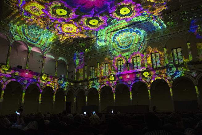 Lights in bold colours, such as pink, yellow and green, are being projected to the walls